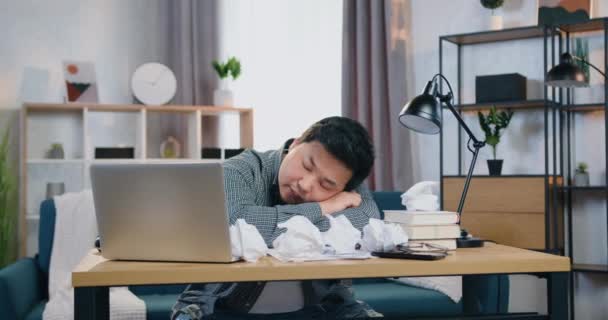 Moe volwassen aziatische man slapen op de kantoortafel bedekt met vele verfrommelde papieren in hedendaagse kantoor — Stockvideo