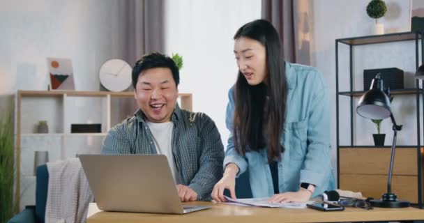 Gut aussehende aufgeregte lächelnde glückliche asiatische Paar feiert Erfolg, wenn gute Nachrichten auf dem Laptop-Bildschirm zu sehen und geben High Five einander — Stockvideo