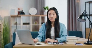 İyi görünümlü, kendine güvenen, kulaklıklı, mikrofonlu, akıl hocası veya hocasıyla video görüşmesinde kameraya poz veren zeki, modern Asyalı genç kızın ön görüntüsü, uzaktan öğrenme kavramı.