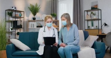 Evinde tedavi gören kadın hastasına danışmak üzere tıbbi maske takan iyi görünümlü, profesyonel bir kadın doktorun ön görüşü.