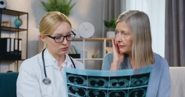 Krásná zkušená užitečné 40-ti leté žena-doktor uklidňující svého pacienta poté, co oba vypadali rentgen sken během domácí návštěvy — Stock video