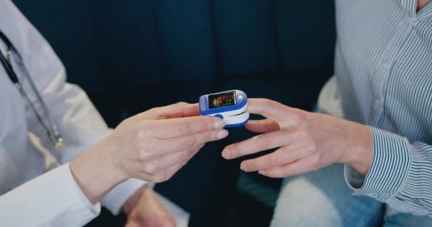 Picture of two people one of which checking oxygen level in blood another-this is doctor revisioning results of measure on gauge display — Stock Video