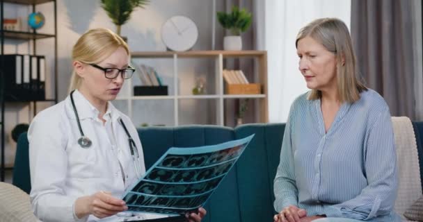 Aanzienlijke positieve ervaren blonde vrouw-arts is tevreden van het resultaat van x-ray scan van de patiënt en het geven van high five met de patiënt tijdens haar bezoek aan huis, gezondheidszorg concept — Stockvideo