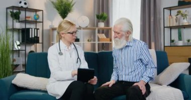 Sevimli, kendine güvenen, yetenekli bir kadın doktor. Evindeki koltukta yaşlı sakallı bir adamla oturuyor ve tablet üzerinde sağlık uygulamasını nasıl kullanacağını söylüyor.
