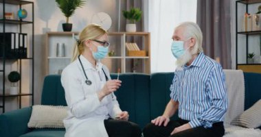 Maskeli sevimli, kendine güvenen profesyonel bir kadın doktor. Yaşlı, sakallı erkek hastaya aşı yapıyor. Maske takıyor.