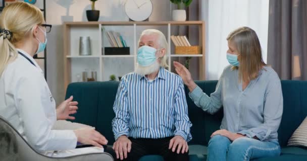 Sympatický užitečný vysoce kvalifikovaný ženský zdravotnický pracovník konzultační starší pár během domácí návštěvy o prevenci v dobách koronavirové pandemie — Stock video