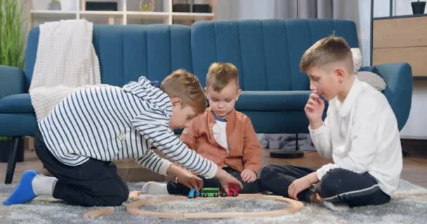 Szerethető boldog elégedett különböző korú testvérek összegyűjtött autó pályán a padlón otthon, és így pacsi egymást, mielőtt játszani — Stock videók