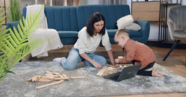 Sevimli yardımsever küçük çocuk, çekici siyah saçlı annesiyle yere saçılmış tahta parçaları topluyor.