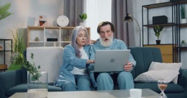 Çekici, mutlu, emekli bir çift çevrimiçi piyangoda iyi haberler alıyor ve ellerini kaldırıp birbirlerine beşlik çakıyor.