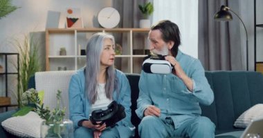 Sevimli, modern, olgun çift, özel 3D gözlüklerini takıp sanal gerçeklik videolarını izlemeden önce evde boş vakitlerini geçiriyorlar.