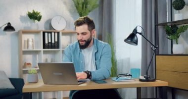 Başarı ve şans kavramı. Çekici, sakallı, genç bir adamın zaferi el kaldırarak kutlaması. Laptop ekranında iyi haberler okurken.