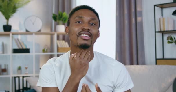 Close up of attractive smiling happy young bearded african american which looking into camera and strocking his hairdo and beard after preparation to go out from home — Stock Video