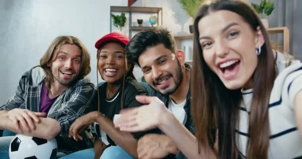 Attraktivt leende glad ung mångsidig grupp vänner tittar in i kameran samtidigt som selfie sitter på soffan hemma under festen — Stockvideo