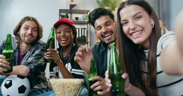 Adorable cheery happy modern young mixed race friends clinking bottles of beer while looking at phone camera to make selfie during party,leisure concept — Stock Video