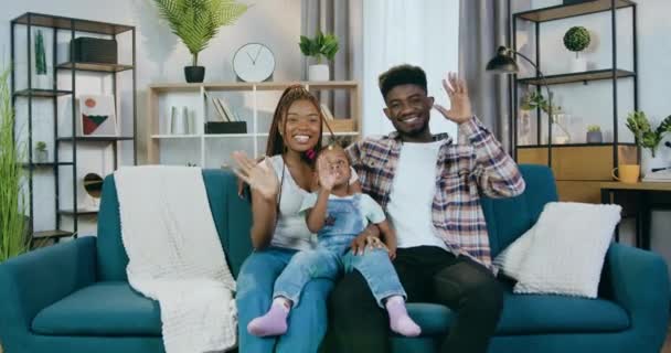 Africká rodina mává rukama a usmívá se na gauči — Stock video