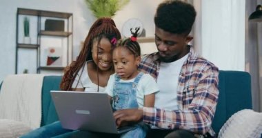 Kızıyla oyun oynamak için dizüstü bilgisayar kullanan Afrikalı bir grup