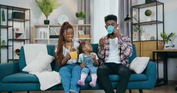 Африканская семья пьет чай и ест печенье дома — стоковое видео