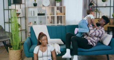 Baba kızıyla şarkı söylerken anne dizüstü bilgisayarda çalışıyor.