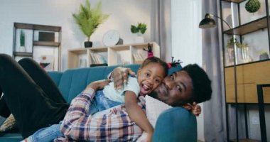 Afrikalı baba, kızıyla sıcak bir kanepede uzanıyor.