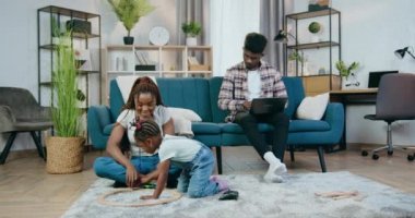 Baba dizüstü bilgisayarla uğraşırken anne kızıyla oynuyor.