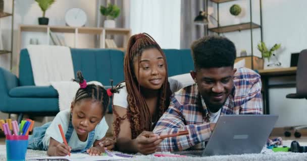 Familia africana joven usando portátil y dibujo en casa — Vídeo de stock