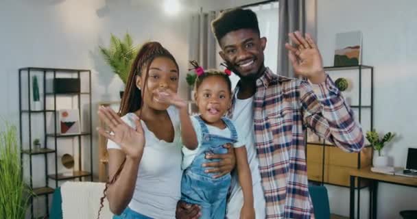 Ouders met dochter glimlachend en zwaaiende handen op camera — Stockvideo