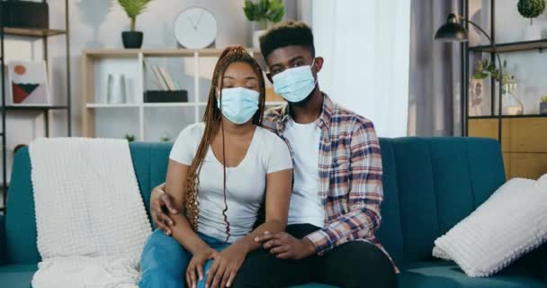 Αφροαμερικανό ζευγάρι κάθεται στον καναπέ με ιατρικές μάσκες — Αρχείο Βίντεο