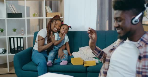 Mère avec sa fille saluant son père qui travaille sur un ordinateur portable — Video