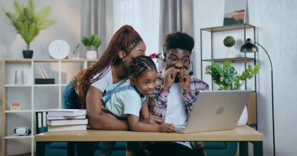 Allegri genitori africani e figlia che utilizzano il computer portatile a casa — Video Stock