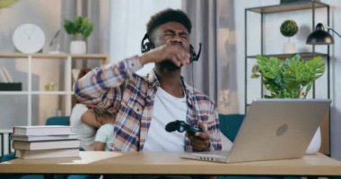 Kulaklıklı hayal kırıklığına uğramış Afrikalı adam dizüstü bilgisayarda oyunu kaybetti