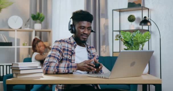 Afro άνθρωπος χρησιμοποιώντας παιχνίδια laptop, ενώ η γυναίκα παίζει με το παιδί — Αρχείο Βίντεο