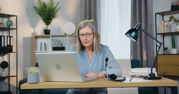 Aantrekkelijke oude vrouw typen op toetsenbord van laptop — Stockvideo