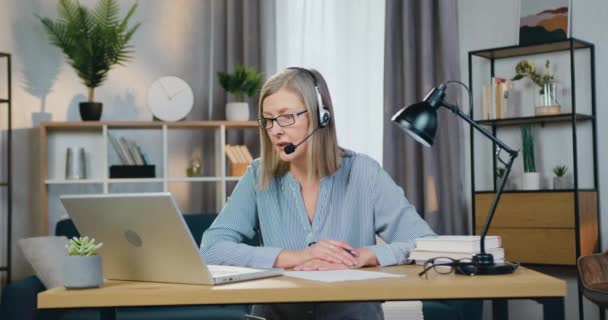 Femme âgée dans un casque ayant une vidéoconférence sur ordinateur portable — Video