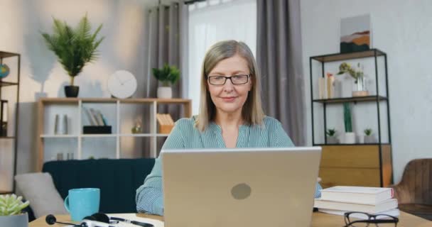 Прекрасная пожилая женщина, пользующаяся ноутбуком в свободное время дома — стоковое видео