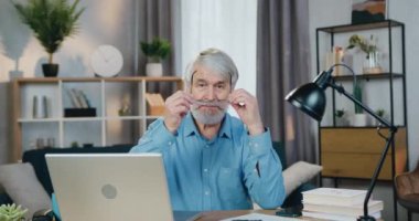 Dizüstü bilgisayarda çalışırken gözlük takan kıdemli bir adam.