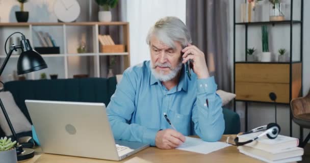 Leeftijd man op zoek naar computerscherm tijdens het praten op mobiele — Stockvideo