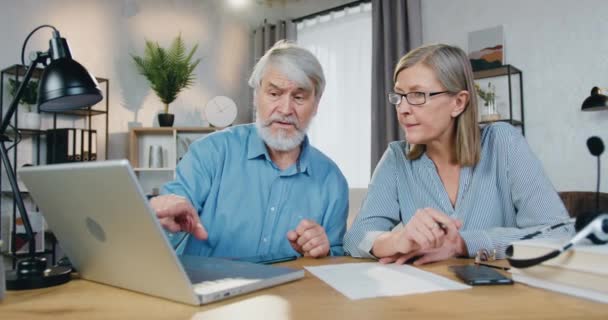 Glada äldre par som använder laptop för att studera tillsammans hemma — Stockvideo