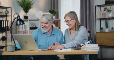 Video araması için modern laptop kullanan pozitif yaşlı çift