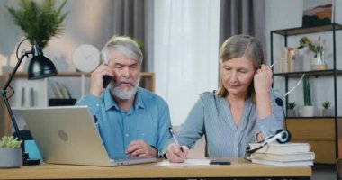 Kadın not alırken, yaşlı adam cep telefonuyla konuşuyor.