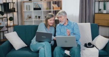 Evde internette sörf yapmak için dizüstü bilgisayar kullanan mutlu bir aile.