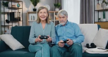 Oyun oynamak için joystick kullanan neşeli, yaşlı bir aile.