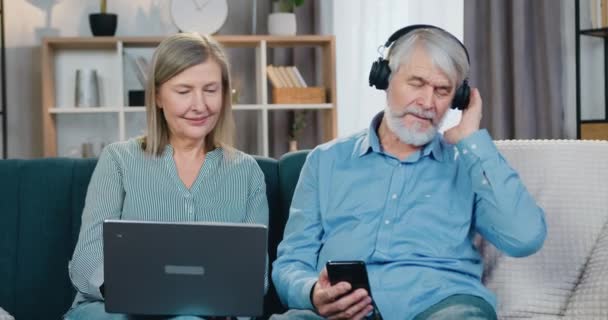 戴耳机的男人喜欢唱歌，而女人则使用笔记本电脑 — 图库视频影像