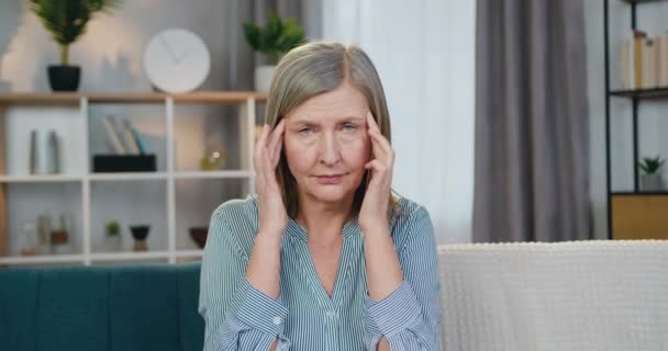 Starší žena dotýká spánků, protože silné bolesti hlavy — Stock video