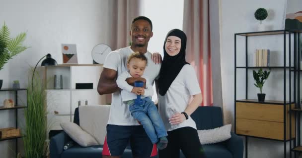 Heerlijk in de stemming sportief modern divers paar met hun kleine zoon voor de camera staan in eigentijds appartement met gelukkige gezichten uitdrukking — Stockvideo