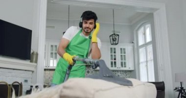 Yakışıklı, çalışkan, sakallı, temizlik şirketinde çalışan, toz böceklerini koltukta süpüren, kulaklıkla modern müziğin tadını çıkaran, hizmet endüstrisi konsepti.