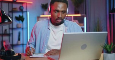 Akşamları evdeki ortaklar ya da müşterilerle video görüşmeleri sırasında önemli notlar yazan sempatik, kendine güvenen Afro-Amerikan vatandaşı.