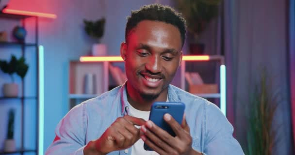 Likable joyeux insouciant jeune afro-américain lire des nouvelles dans les médias sociaux et mettre des marques comme sous-aimé messages dans la soirée à la maison, concept de loisirs — Video