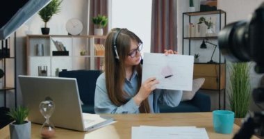 Çekici, yetenekli, kulaklık takan, kameraya video kaydeden, yazılım fırsatları hakkındaki vaazının sonuçlarını açıklayan, modern, yetenekli genç bir kız.