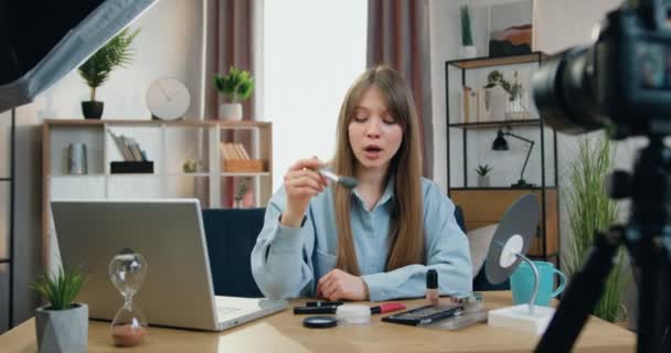 Blogger de belleza femenina de éxito positivo agradable en vivo hablando con la audiencia en línea sobre productos de maquillaje en la cámara en el estudio en casa, concepto de blogueo — Vídeo de stock