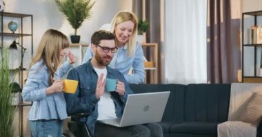 Modern iletişim konsepti. Yakışıklı, gülümseyen, sakat bir adam, açık renk saçlı, gülümseyen bir karısı ve 10 yaşındaki tatlı kızının evde bilgisayarında akrabalarıyla görüntülü sohbet etmesi.